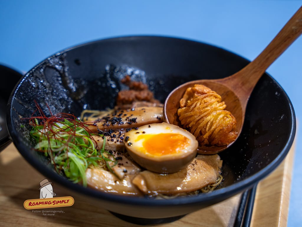 Authentic Japanese ramen with marinated egg and side dishes served at a Singapore restaurant, RoamingSimply travel guide.