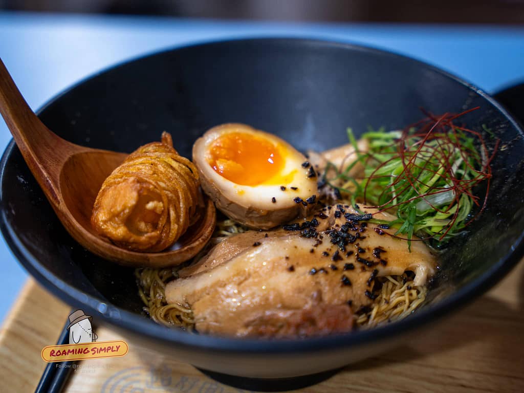 Authentic Japanese ramen with marinated egg and side dishes served at a Singapore restaurant, RoamingSimply travel guide.