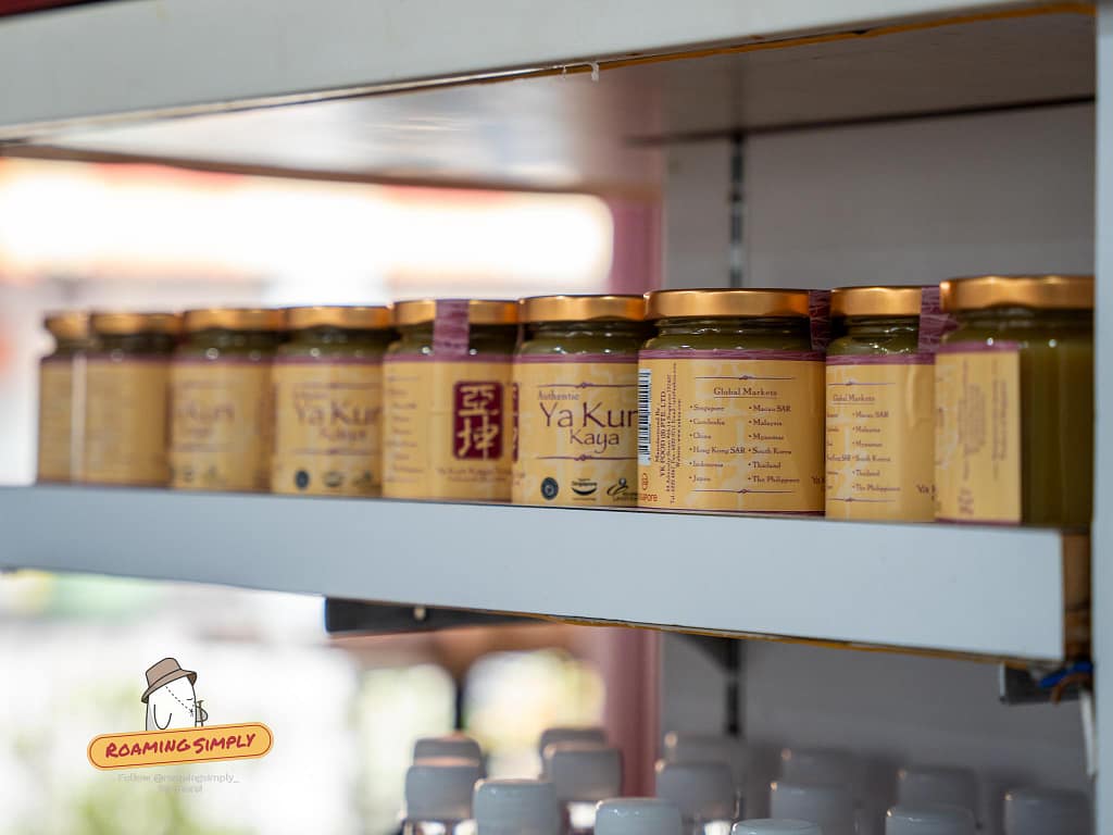 A neat row of authentic Ya Kun Kaya coconut jam jars displayed on a store shelf in Singapore.