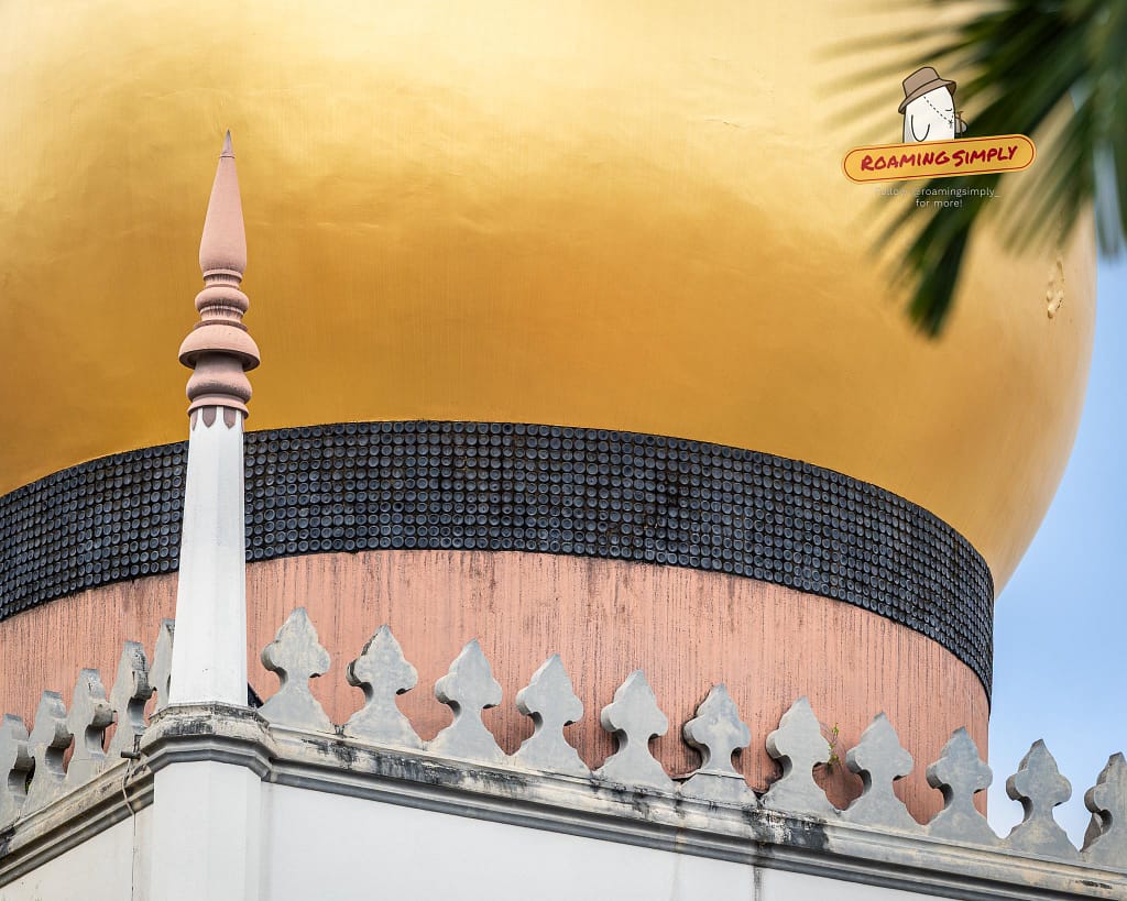 Close-up of the Sultan Mosque's golden dome in Singapore, highlighting the unique black band made of donated glass bottles at its base.