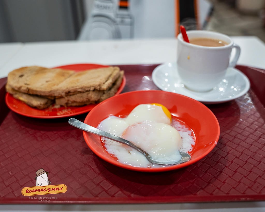 A close-up of the famous Ya Kun Kaya Toast Set A, featuring crispy kaya toast, two soft-boiled eggs, and hot coffee on a red tray in Singapore.