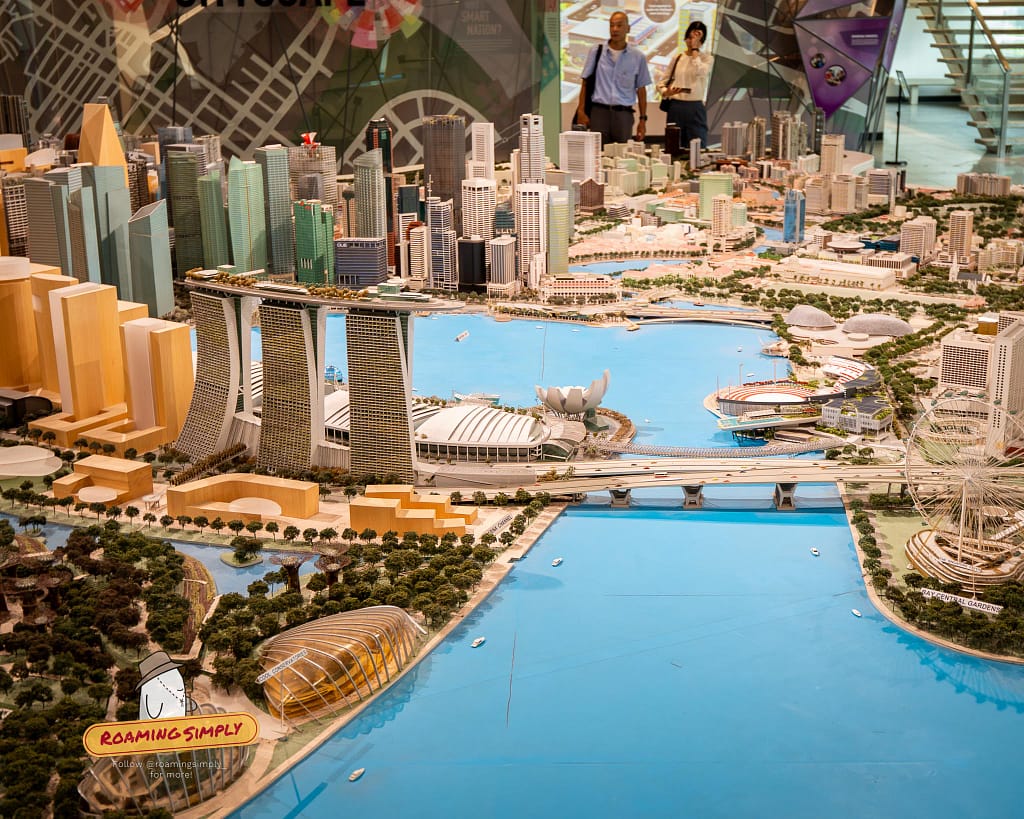 Elevated exterior photograph of the modern glass facade of the Singapore City Gallery and URA Centre building at 45 Maxwell Road on a bright day.
