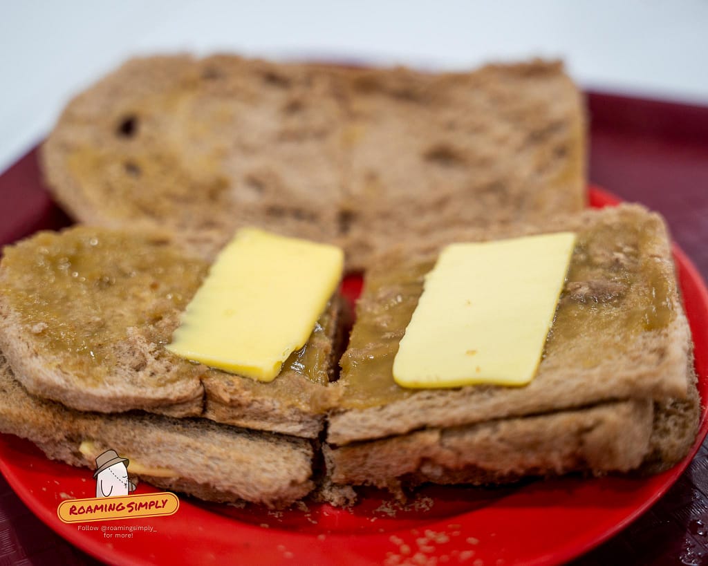 Close-up of Ya Kun Kaya Toast open to reveal thick slices of butter and rich coconut kaya jam on toasted brown bread in Singapore.
