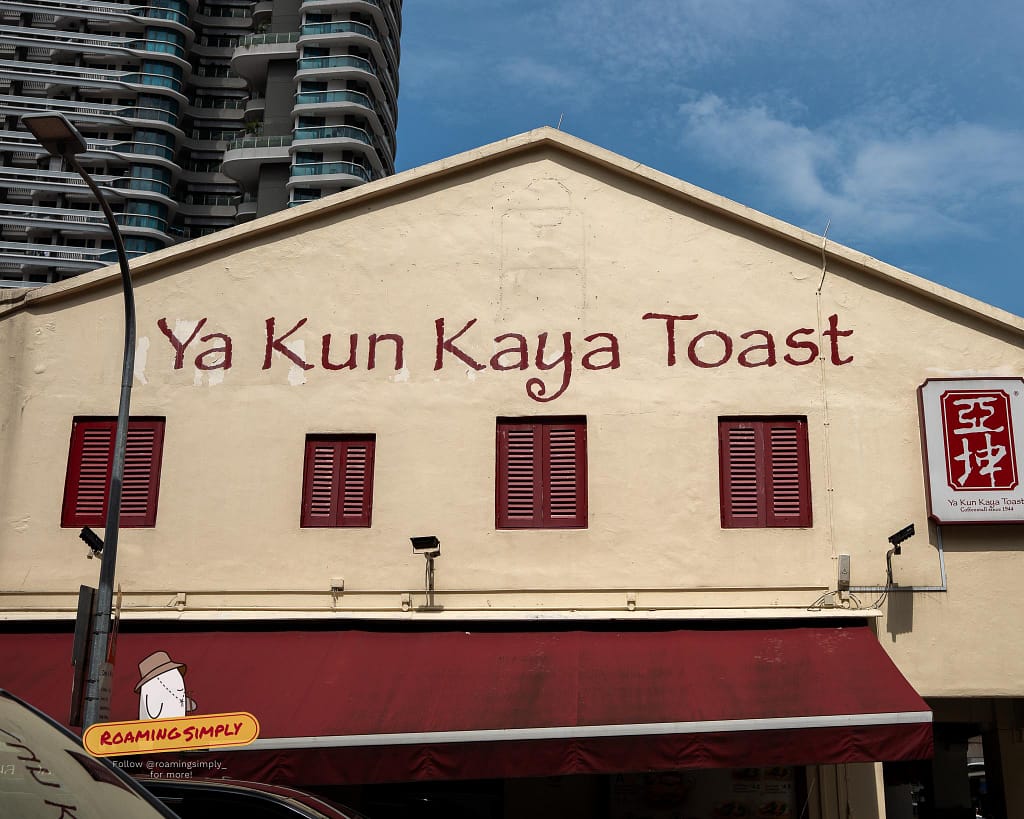 The prominent exterior of the Ya Kun Kaya Toast heritage building in Singapore, featuring large red painted lettering and classic wooden shutters.