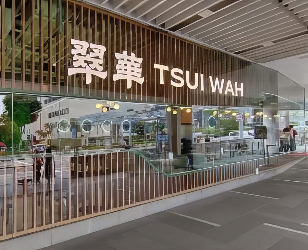 Exterior view of a modern Tsui Wah restaurant storefront in Singapore, featuring large glass windows, vertical wooden slats, and prominent white illuminated signage in English and Chinese.