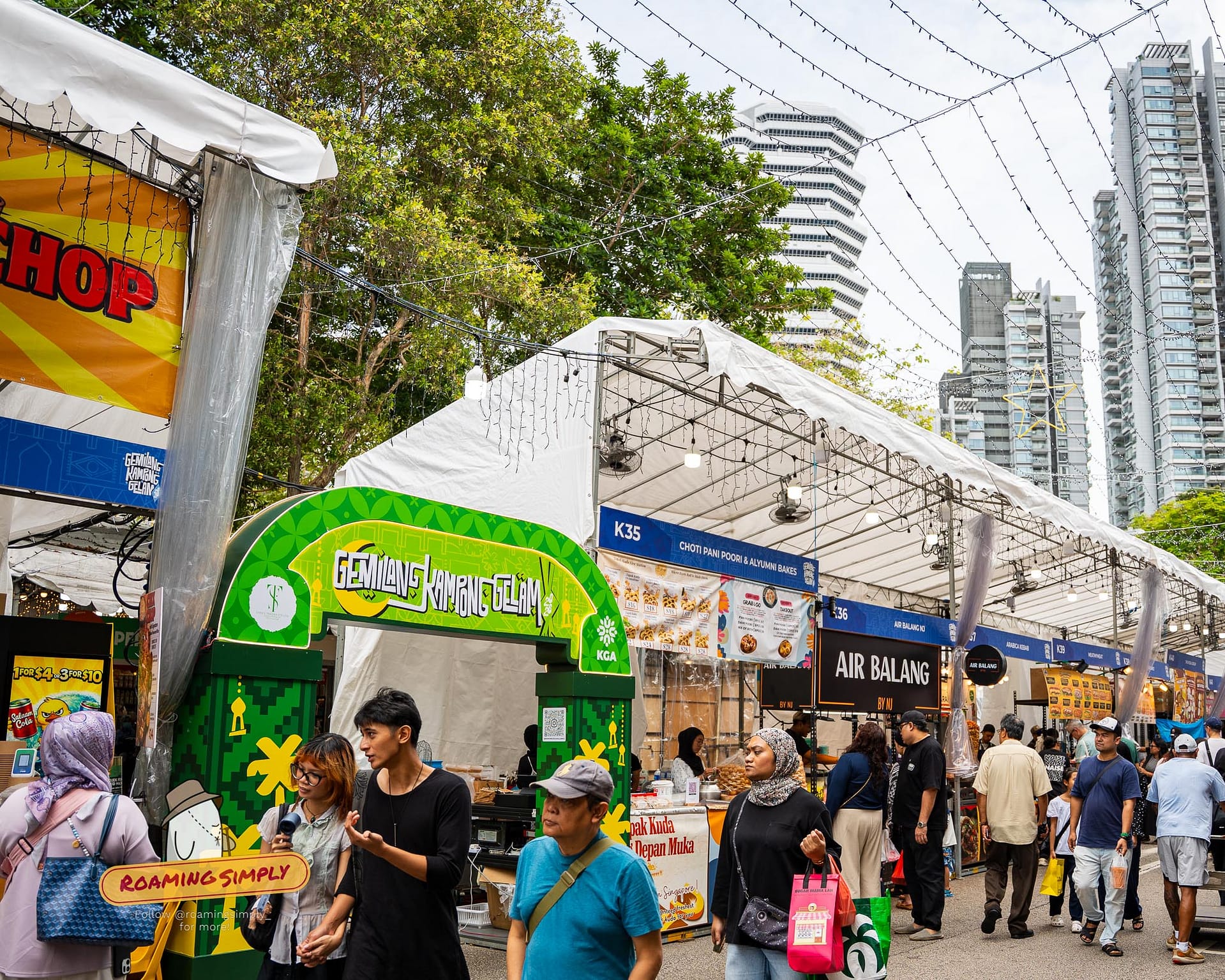 Crowds exploring the bustling Kampong Glam Bazaar in Singapore, featuring vibrant street food stalls and festive decorations.